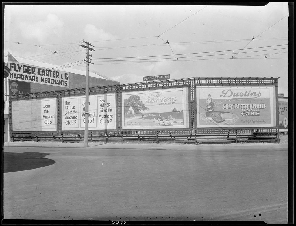 Painted advertising hoardings beside a road, around 1930