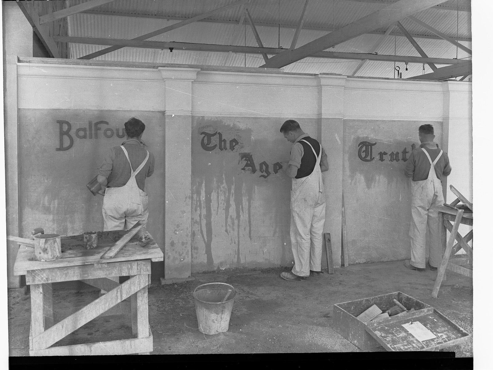 Three sign writers painting the names Balfours, The Age and Truth onto a wall, South Australia